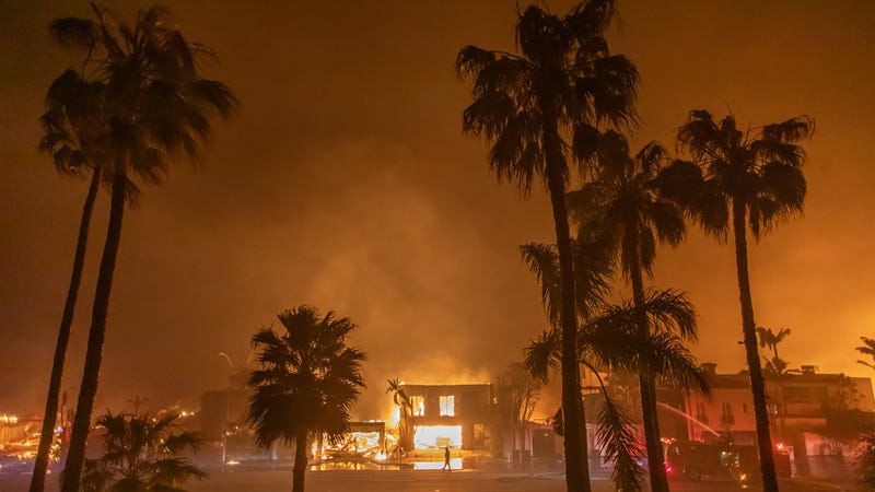 Firefighter watches flames from Palisades Fire burning homes