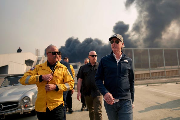California Governor Gavin Newsom (R) tours the downtown business district of Pacific Palisades as the Palisades Fire continues to burn on January 8, 2025 in Los Angeles, California. Fueled by intense Santa Ana Winds, the Palisades Fire has grown to over 2,900 acres and 30,000 people have been ordered to evacuate while a second major fire continues to burn near Eaton Canyon in Altadena. (Photo by Eric Thayer/Getty Images)