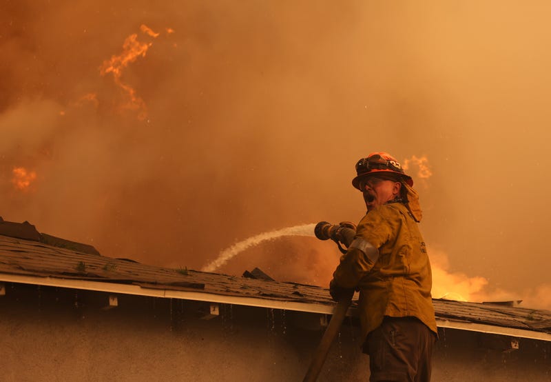 firefighter spraying water on house
