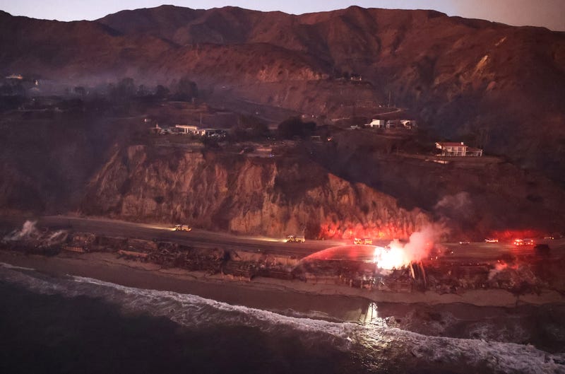 In an aerial view, destroyed homes (bottom) are seen as the Palisades Fire continues to burn on January 09, 2025 in Malibu, California.