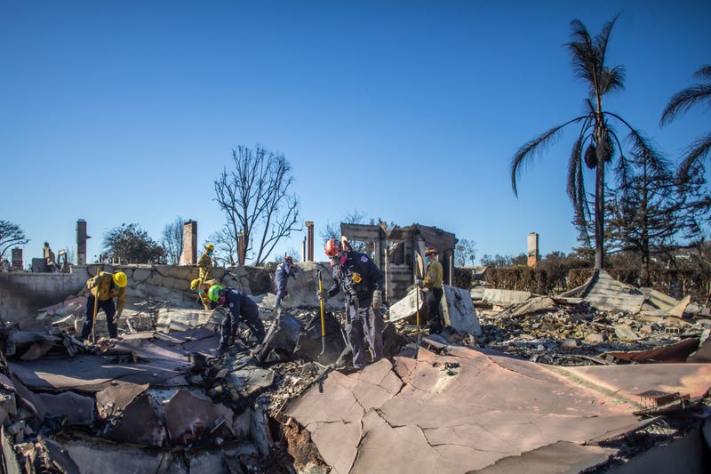 Los Angeles Fire Fighters and Sacramento Fire Fighters Urban Search & Rescue team inspect a burned house from the Palisades Fire in the Pacific Palisades neighborhood on January 16, 2025 in Los Angeles, California.