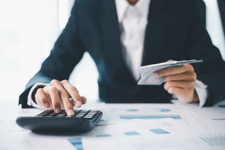 Woman typing on calculator holding documents