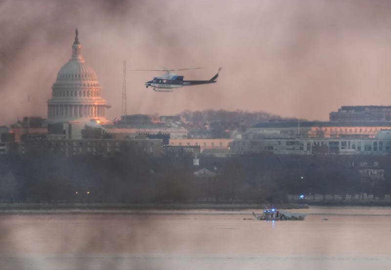 A helicopter flies near the crash site of the American Airlines plane on the Potomac River after the plane crashed on approach to Reagan National Airport on January 30, 2025 in Arlington, Virginia