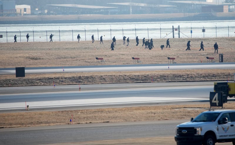 Investigators walk the grounds of the Reagan National Airport as they work near the crash last night of the American Airlines plane on the Potomac River as it approached the Reagan National Airport on January 30, 2025 in Arlington, Virginia