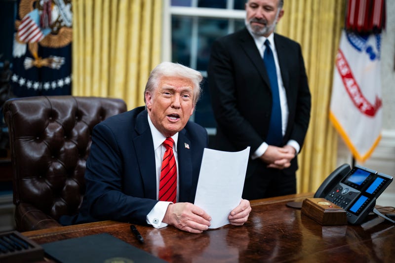 President Donald Trump, flanked by Commerce Secretary nominee Howard Lutnick, speaks with reporters and signs executive orders in the Oval Office at the White House on Feb. 10, 2025