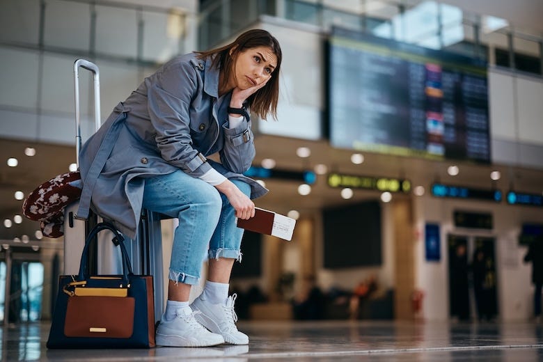 Stressed woman sitting on her luggage at the airport