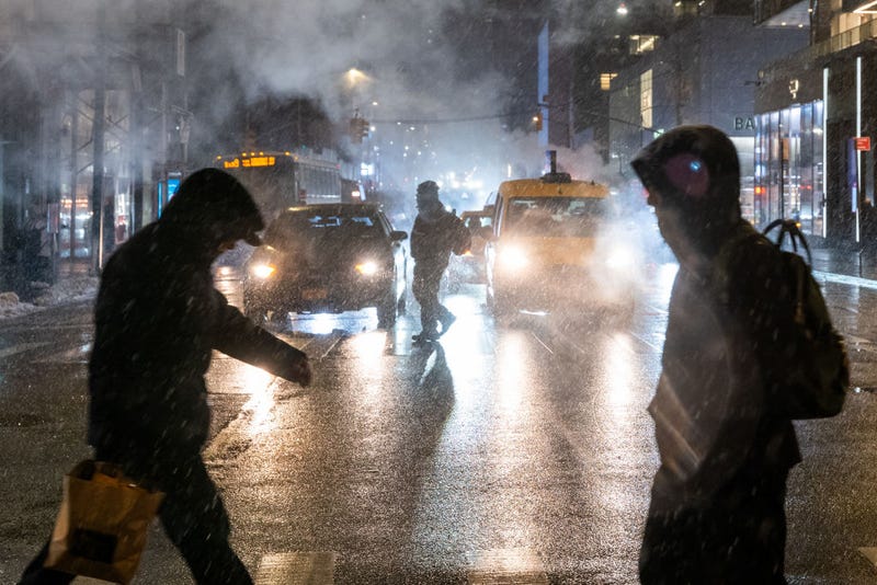 People walk through Manhattan during evening snow on Feb. 11, 2025 in New York City.