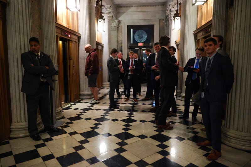 U.S. Sen. John Fetterman (D-PA) (L) waits for an elevator with staffers outside the Senate Chambers during a Senate "vote-a-rama" on February 20, 2025 in Washington, DC. The Senate is holding an all-night marathon vote, referred to as a "vote-a-rama", as Republicans look to pass their GOP budget resolution. 