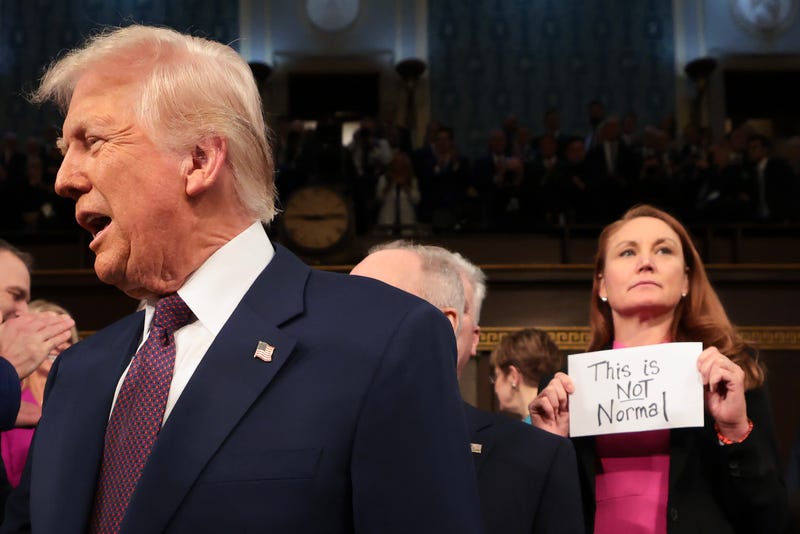 U.S. President Donald Trump arrives for his speech to a joint session of Congress as Rep. Melanie Stansbury (D-NM) holds a sign reading "This is not normal" at the U.S. Capitol on March 4.