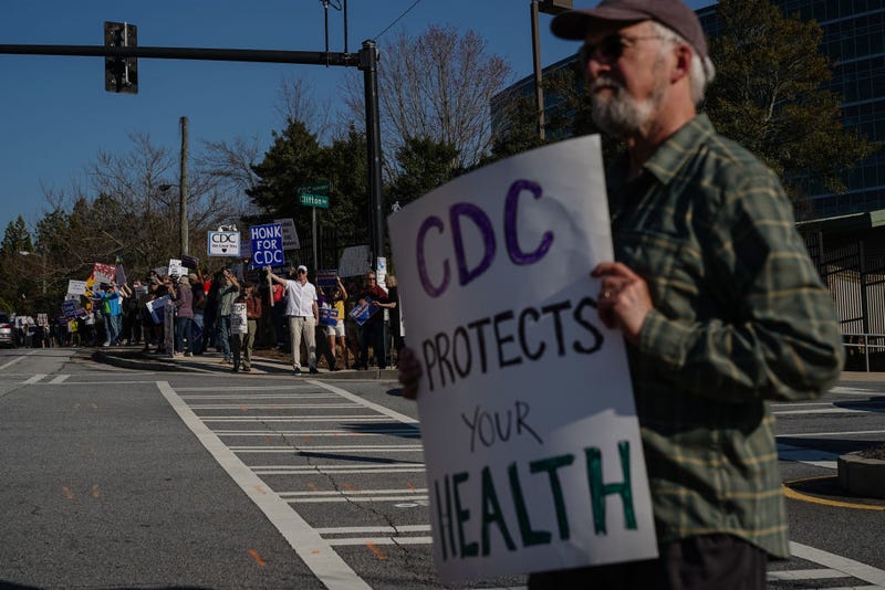 People protesting personnel cuts at the Centers for Disease Control (CDC) hold signs outside the organization's main headquarters on March 12, 2025 in Atlanta, Georgia. 