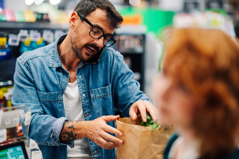Man grabbing paper grocery bag from checkout