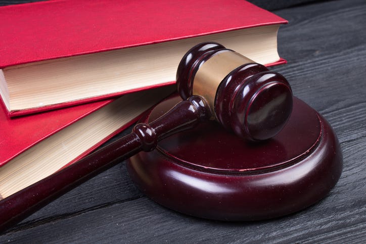 Law concept - Open law book with a wooden judges gavel on table in a courtroom or law enforcement office on blue background. Copy space for text