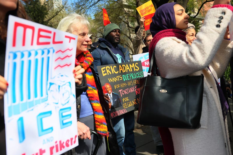 People hold signs during a press conference outside of City Hall on April 10, 2025