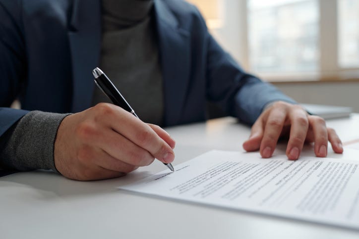 Closeup of unrecognizable businessman signing contract in office with focus on male hand holding pen copy space
