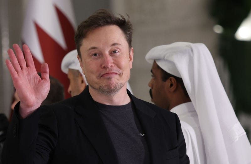 Elon Musk waves as he arrives for a state dinner at the Lusail Palace in Qatar