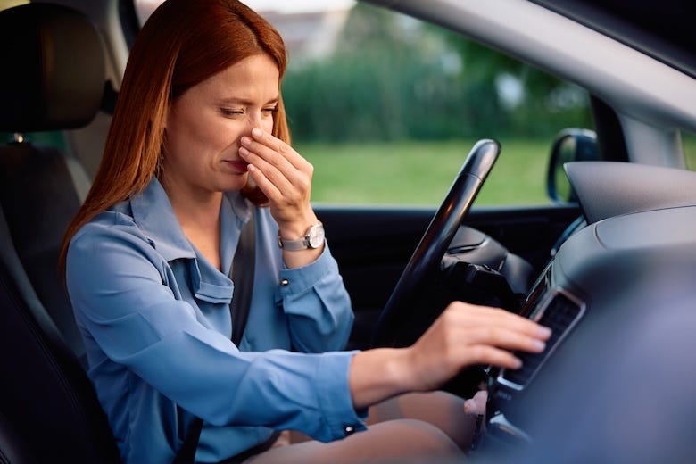 Woman pinching her nose shut while driving her car