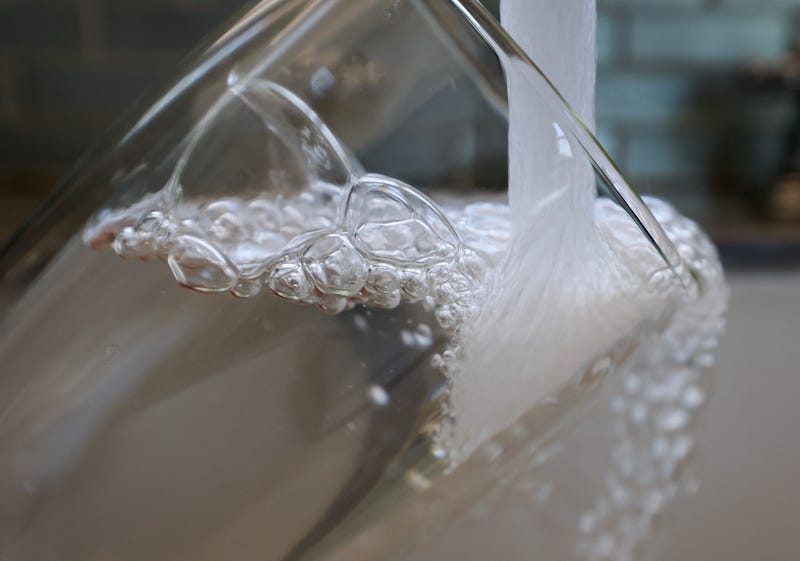 Water pours from a faucet into a glass.