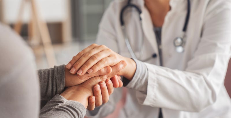 A doctor warmly claps her patient's hands as they celebrate good news