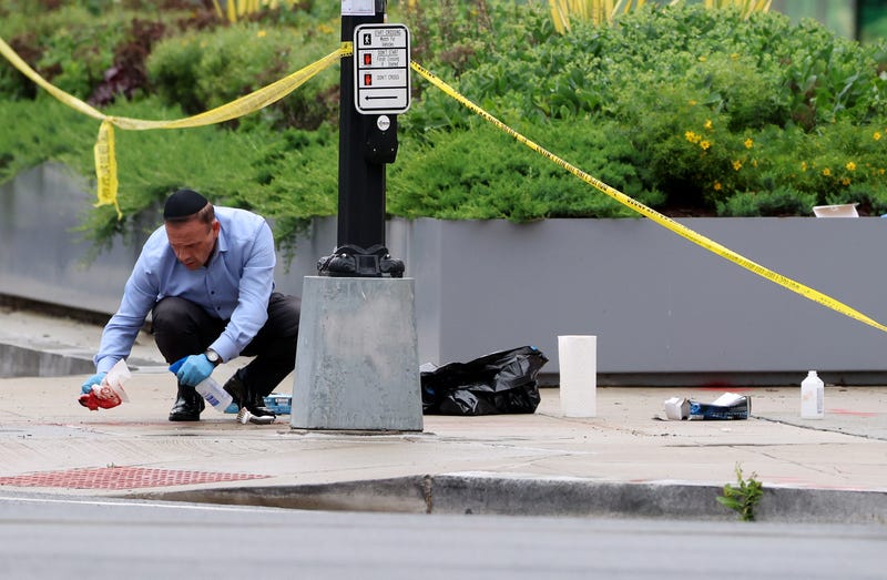 An embassy official cleans blood off the sidewalk at the shooting location outside of the Lillian and Albert Small Capital Jewish Museum on May 22, 2025, in Washington, D.C.