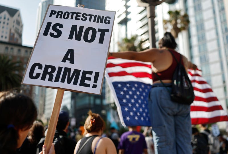 LOS ANGELES, CALIFORNIA - JUNE 11: A person holds a "Protesting Is Not A Crime!" sign as people demonstrate before marching downtown as protests against ICE immigration raids continue in the city on June 11, 2025 in Los Angeles, California. Tensions in the city remain high with daily protests after the Trump administration called in the National Guard and the Marines against the wishes of Gov. Gavin Newsom and city leaders.