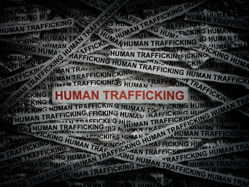 Human Trafficking graphic showing the word on small strips of paper. Most are in black and white. One, front and center, is in red.