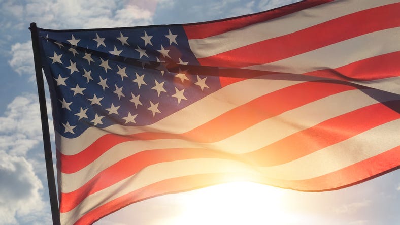 close up American flag waving in the wind against sunset