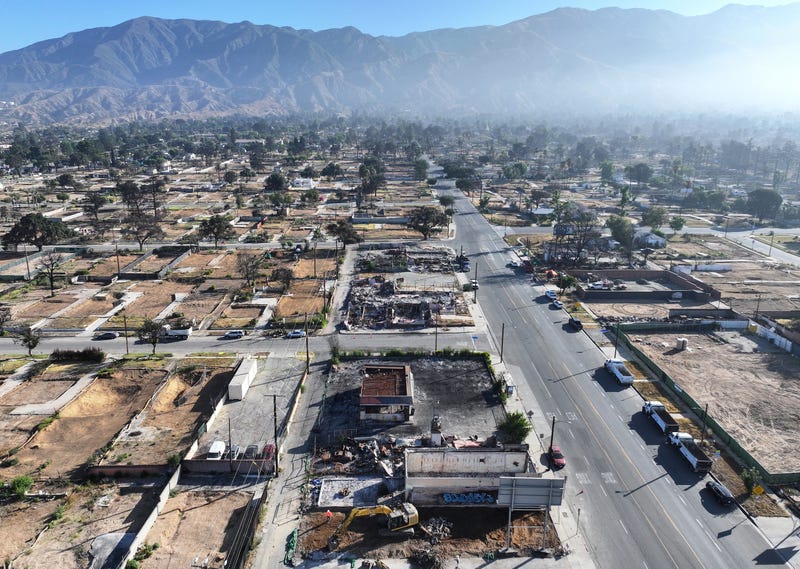 An aerial view of workers clearing a business (BELOW C) which burned in the Eaton Fire on July 07, 2025 in Altadena, California. Today is the six month anniversary of the Eaton and Palisades fires which claimed 30 lives and left more than 16,000 structures destroyed. 