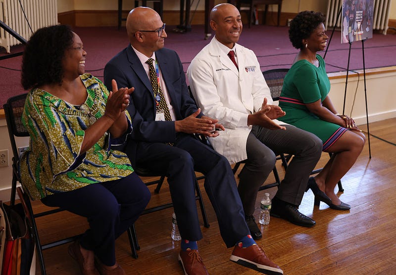 Dr. Geralde Gabeau, Founder and Executive Director of the Immigrant Families Services Institute laughs as she sits beside Jay Trivedi, CEO of Upham's Corner Community Health Center, Dr. Alister Martin, Founder and Managing Director of Link Health and Stephanie Garrett-Stearns, Senior Vice President of Communications and Fund Development for The Community Builders, who all received grant money for their respective foundations at the Great Hall at Codman Square Health Center on July 28, 2025.