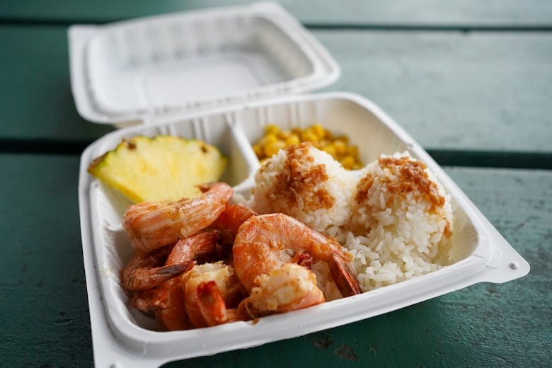 Garlic shrimp (Hawaiian style) with a side of rice and pineapple in a takeout box