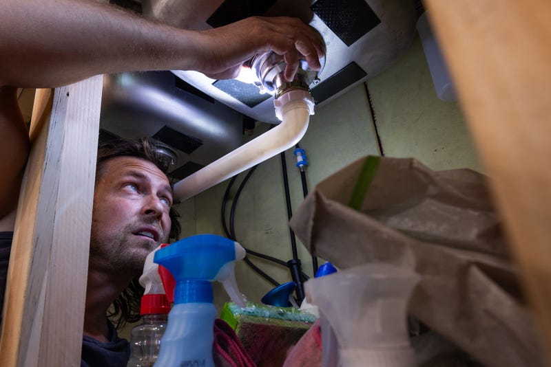 plumber inspecting under a sink with flashlight