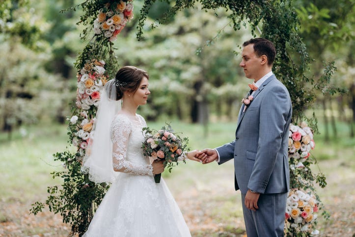 wedding ceremony of the marriage of a guy and a girl against the backdrop of an arch on a forest path