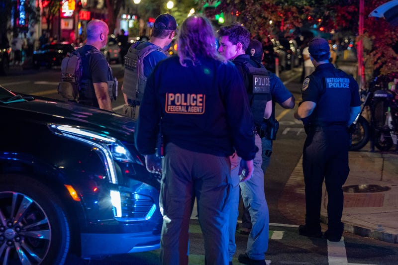Federal agents standing around car in busy street