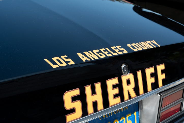 Close-up view of the rear trunk of a Los Angeles County Sheriff vehicle, showing the official sheriff lettering and part of a California license plate.