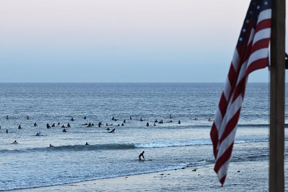  People surf on the Pacific Ocean at a beach located outside the Palisades Fire burn zone on August 26, 2025 in Malibu, California. The U.S. Army Corps of Engineers has begun debris removal at the final “opt-in” property located in the Palisades Fire recovery area with 1,152,714 tons of debris removed from the area during the operation which cleared over 4,000 properties. (Photo by Mario Tama/Getty Images)