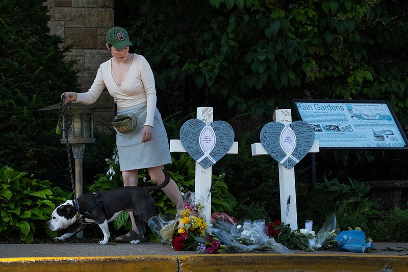 A woman walks her dog past a memorial to yesterday's shooting victims in front of Annunciation Catholic Church on August 28, 2025 in Minneapolis, Minnesota. 