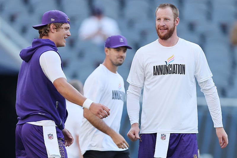 J.J. McCarthy #9 and Carson Wentz #11 of the Minnesota Vikings look on prior to the game against the Chicago Bears at Soldier Field on September 08, 2025 in Chicago, Illinois. It's now Wentz's turn to run the offense with McCarthy out with a sprained ankle.