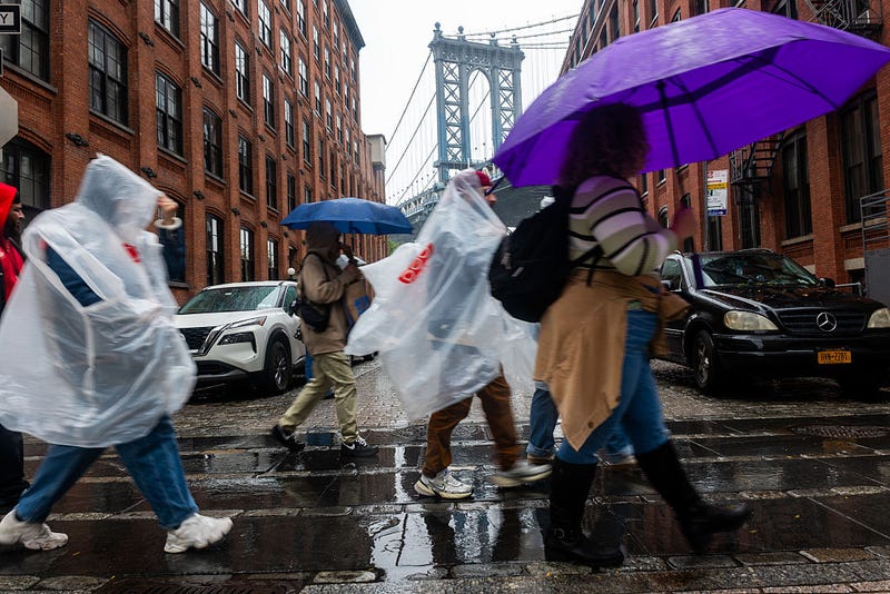 People walk through Brooklyn in the rain as New York City experiences wind and rain associated with a nor’easter storm moving through the region on October 13, 2025.