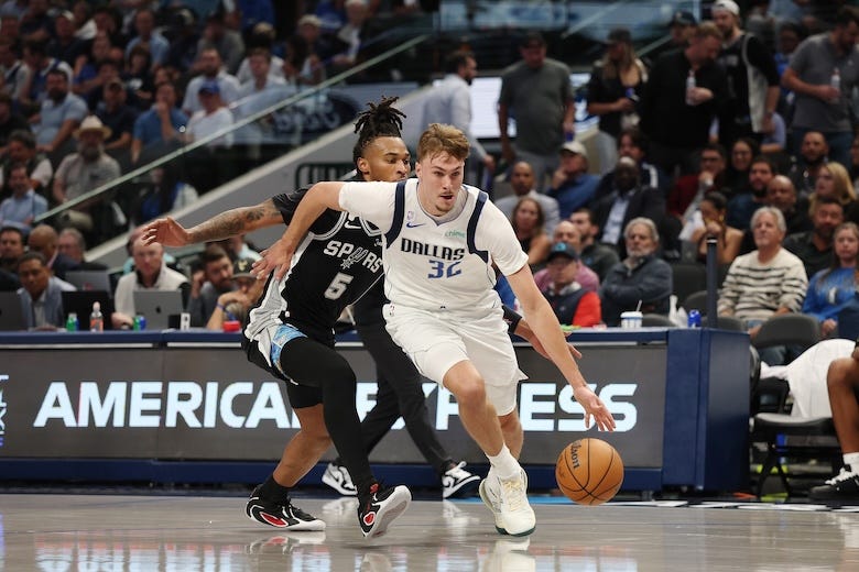 Cooper Flagg #32 of the Dallas Mavericks drives around Stephon Castle #5 of the San Antonio Spurs during a game at American Airlines Center on October 22, 2025 in Dallas, Texas