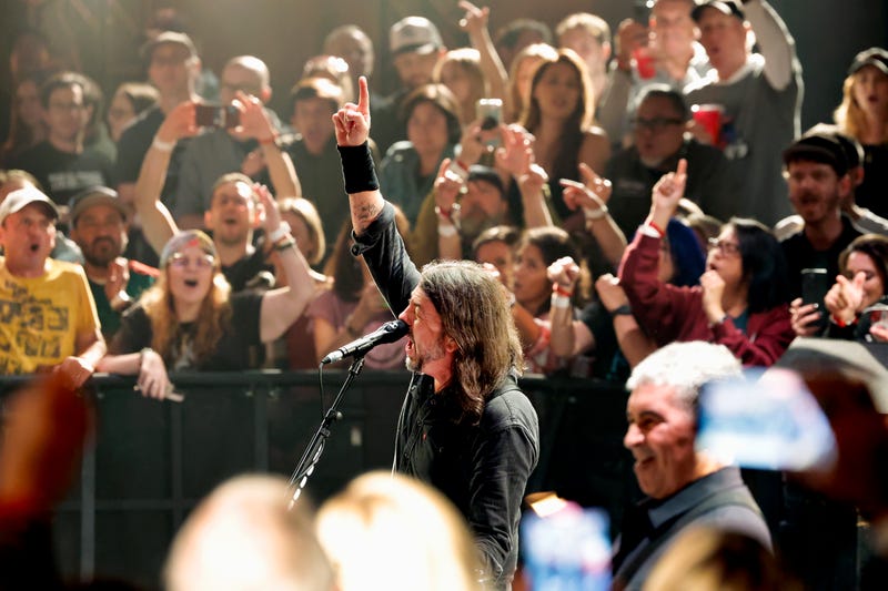 Singer Dave Grohl in middle of crowd singing with his hand up