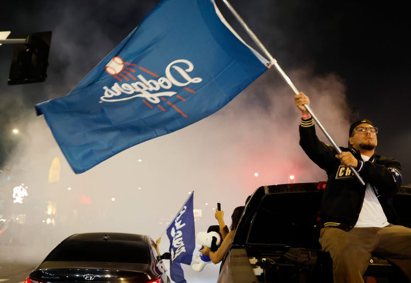 man with dodger flag sitting on back of a car