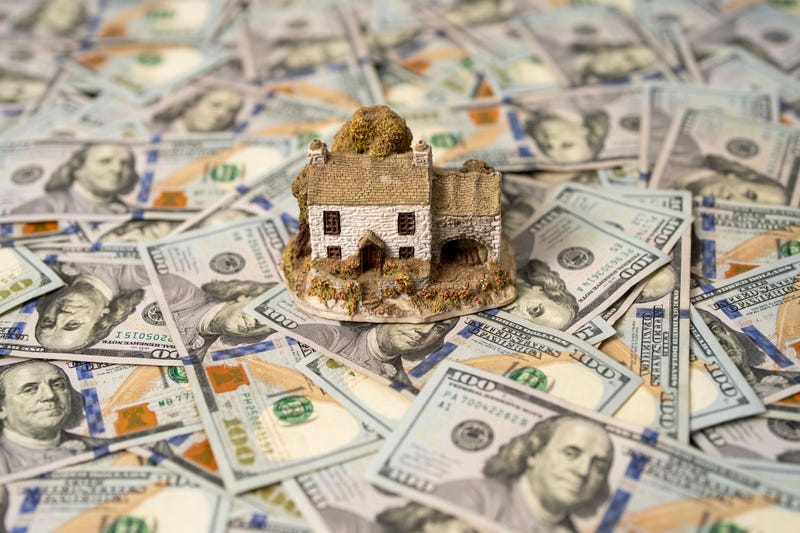 A small model of a house surrounded by $100 bills