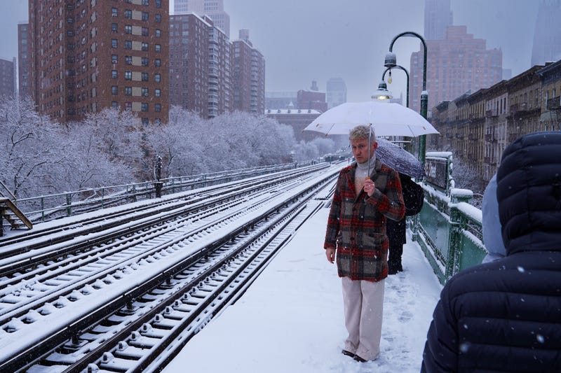 A man waits for a train during a snowstorm in December