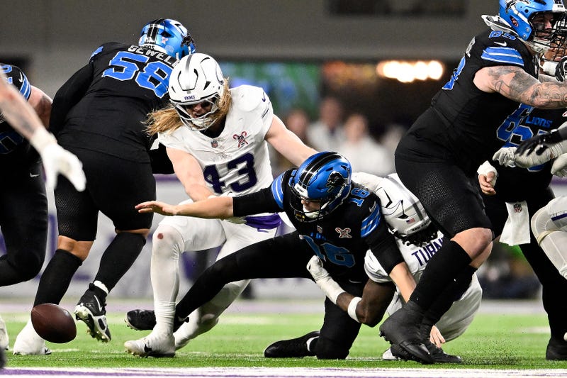 Jared Goff #16 of the Detroit Lions fumbles the ball against Dallas Turner #15 and Andrew van Ginkel #43 of the Minnesota Vikings during the fourth quarter at U.S. Bank Stadium on December 25, 2025 in Minneapolis, Minnesota. 