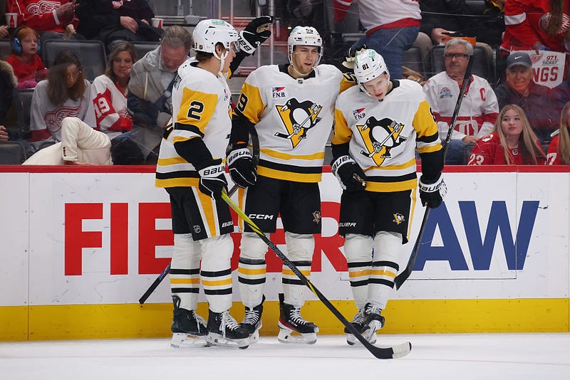 Yegor Chinakhoy #59 of the Pittsburgh Penguins celebrates his first period goal with Rutger McGroarty #2 and Ben Kindel #81 while playing the Detroit Red Wings at Little Caesars Arena on January 03, 2026 in Detroit, Michigan. 