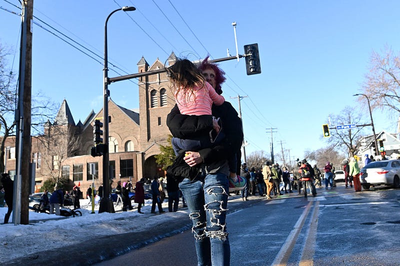 A person carries a child away from the scene where ICE agents were confronted by protestors after they arrested people from a residence on January 13, 2026 in Minneapolis, Minnesota.  