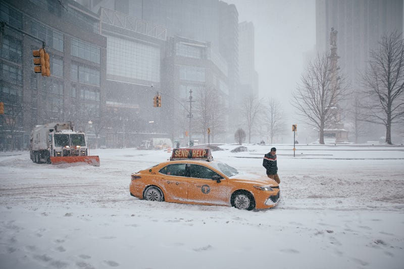 A taxi driver gets out of his car after it becomes stuck in the snow at Columbus Circle on Jan. 25, 2026