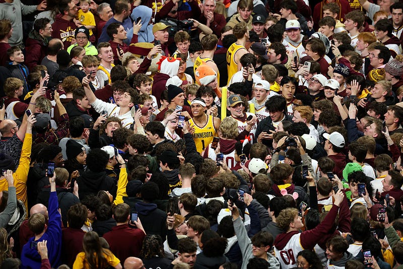 Isaac Asuma #1 of the Minnesota Golden Gophers (C) celebrates the win as fans storm the court after the game against the Michigan State Spartans at Williams Arena on February 04, 2026 in Minneapolis, Minnesota. The Golden Gophers defeated the Spartans 76-73. 