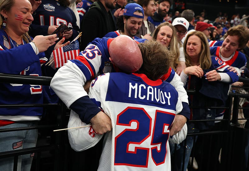 MILAN, ITALY - FEBRUARY 22: Gold medalist Charlie McAvoy #25 of Team United States celebrates with a fan following the Men's Gold Medal match between Canada and the United States on day 16 of the Milano Cortina 2026 Winter Olympic games at Milano Santagiulia Ice Hockey Arena on February 22, 2026 in Milan, Italy. (Photo by Gregory Shamus/Getty Images)