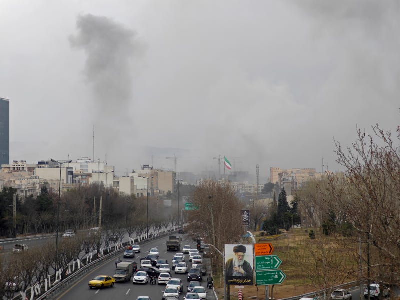 A plume of smoke rises above road traffic after an explosion on March 2, 2026 in Tehran, Iran. The United States and Israel continued their joint attacks that erupted on February 28.