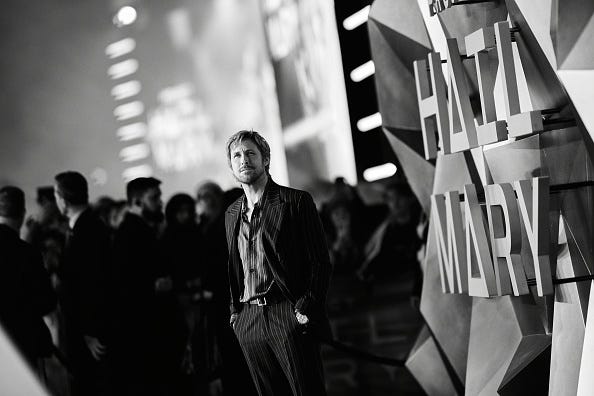 Ryan Gosling stands in front of a giant Project Hail Mary sign